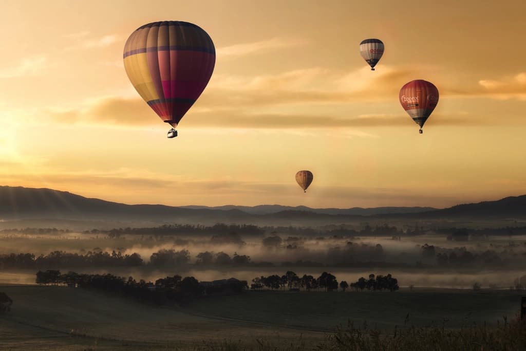 Montgolfieres au-dessus d'une vallee brumeuse au lever du jour